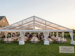 Clear roof clear span tent hosting a lawn reception, with a for sale sign in front.